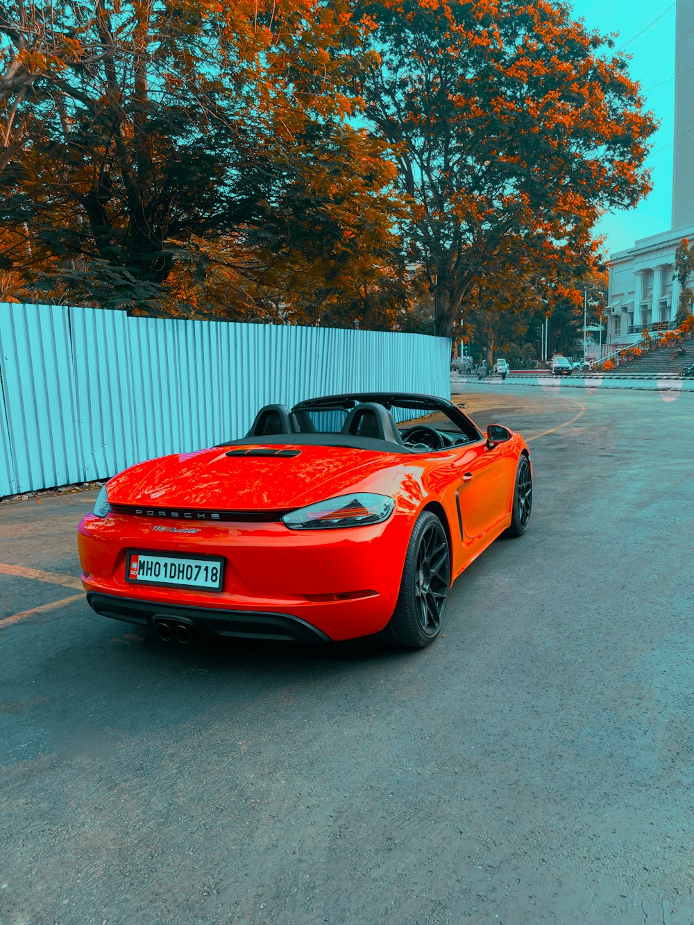 a red sports car parked in front of a white fence