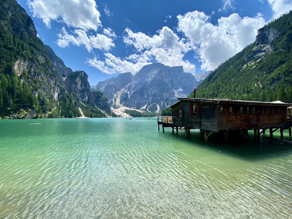 a house on stilts in a lake with mountains in the background