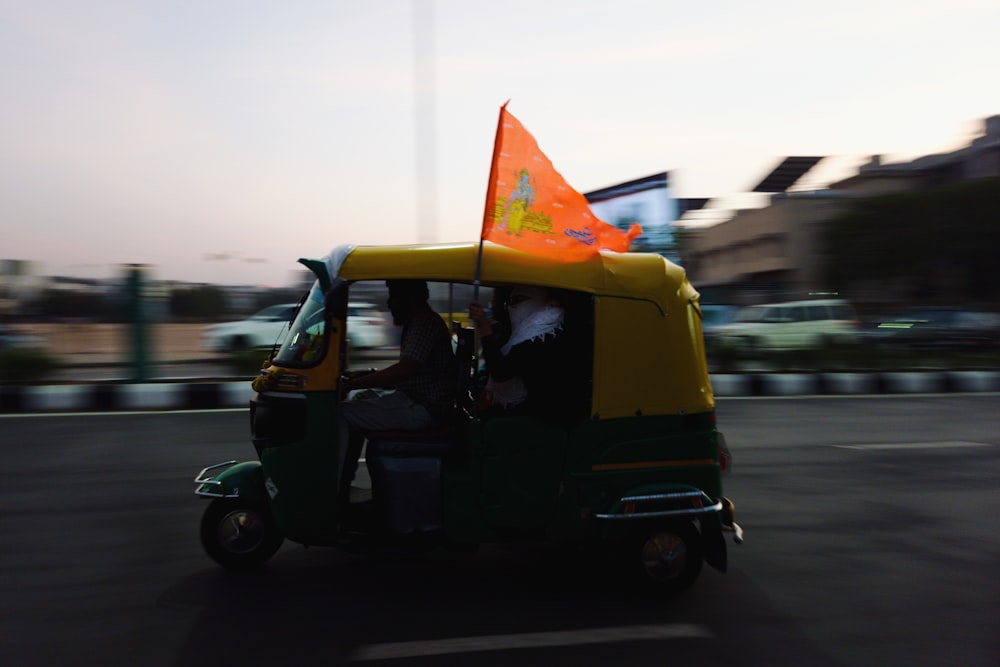 a man driving a small green and yellow vehicle