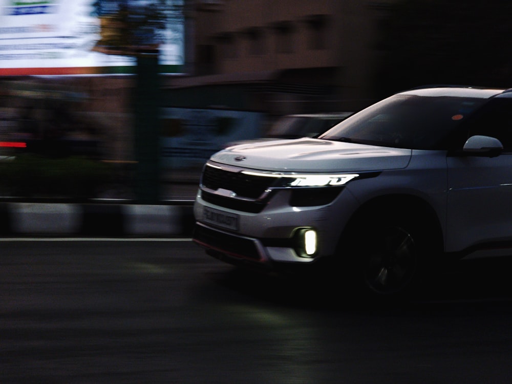 a white suv driving down a street at night