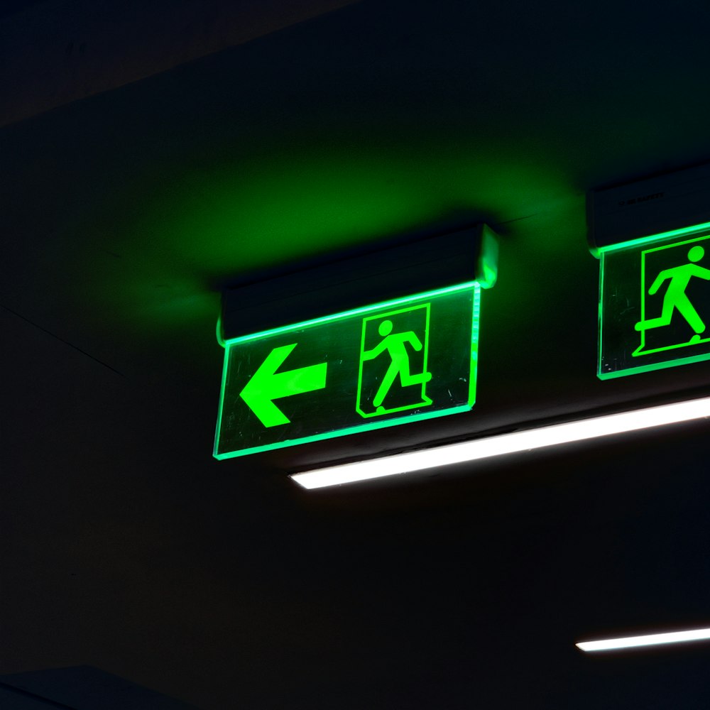 a couple of green signs hanging from the ceiling