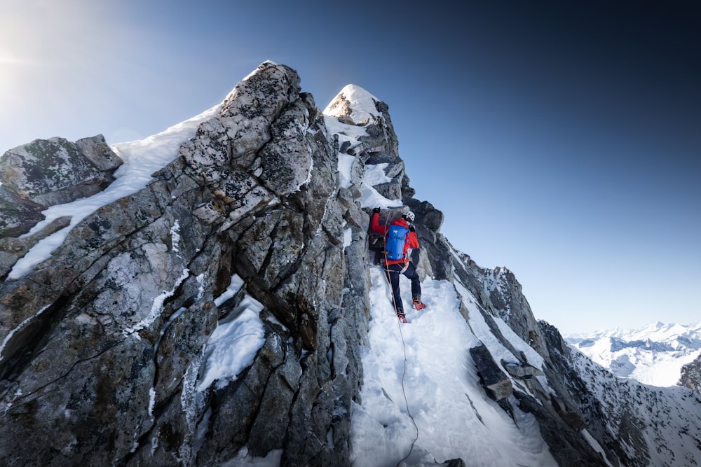 a man climbing up the side of a snow covered mountain