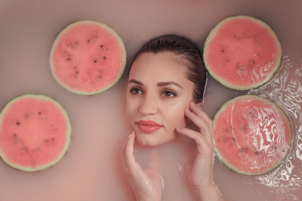 a woman in a bubble bath with watermelon slices