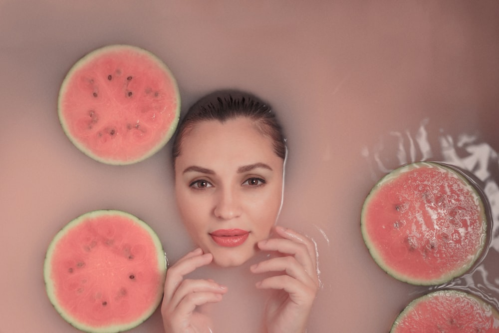 a woman in a bubble bath with slices of watermelon