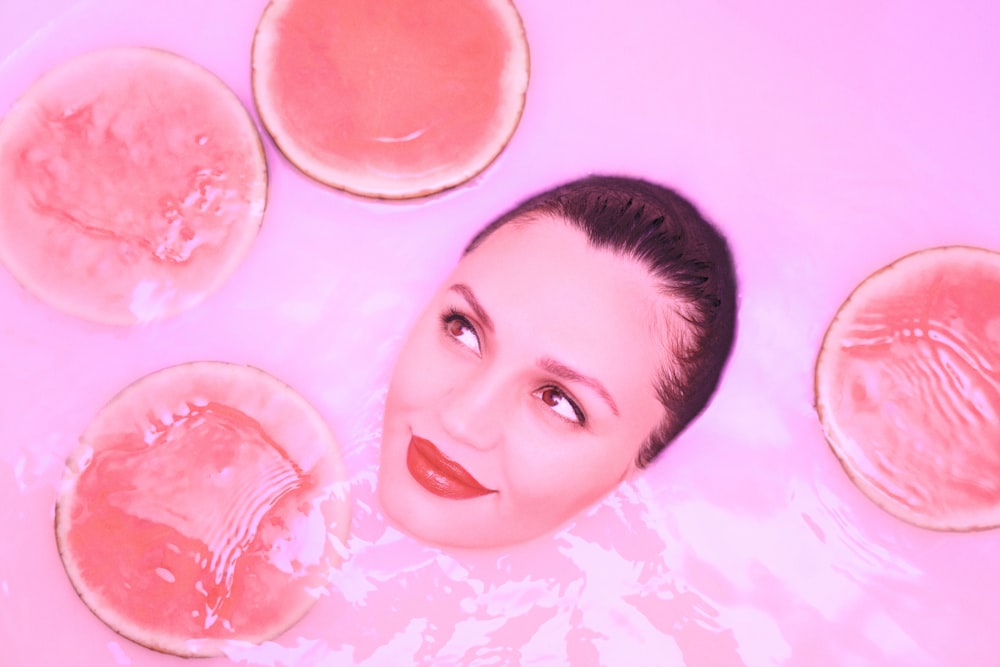 a woman in a hot tub with three slices of watermelon