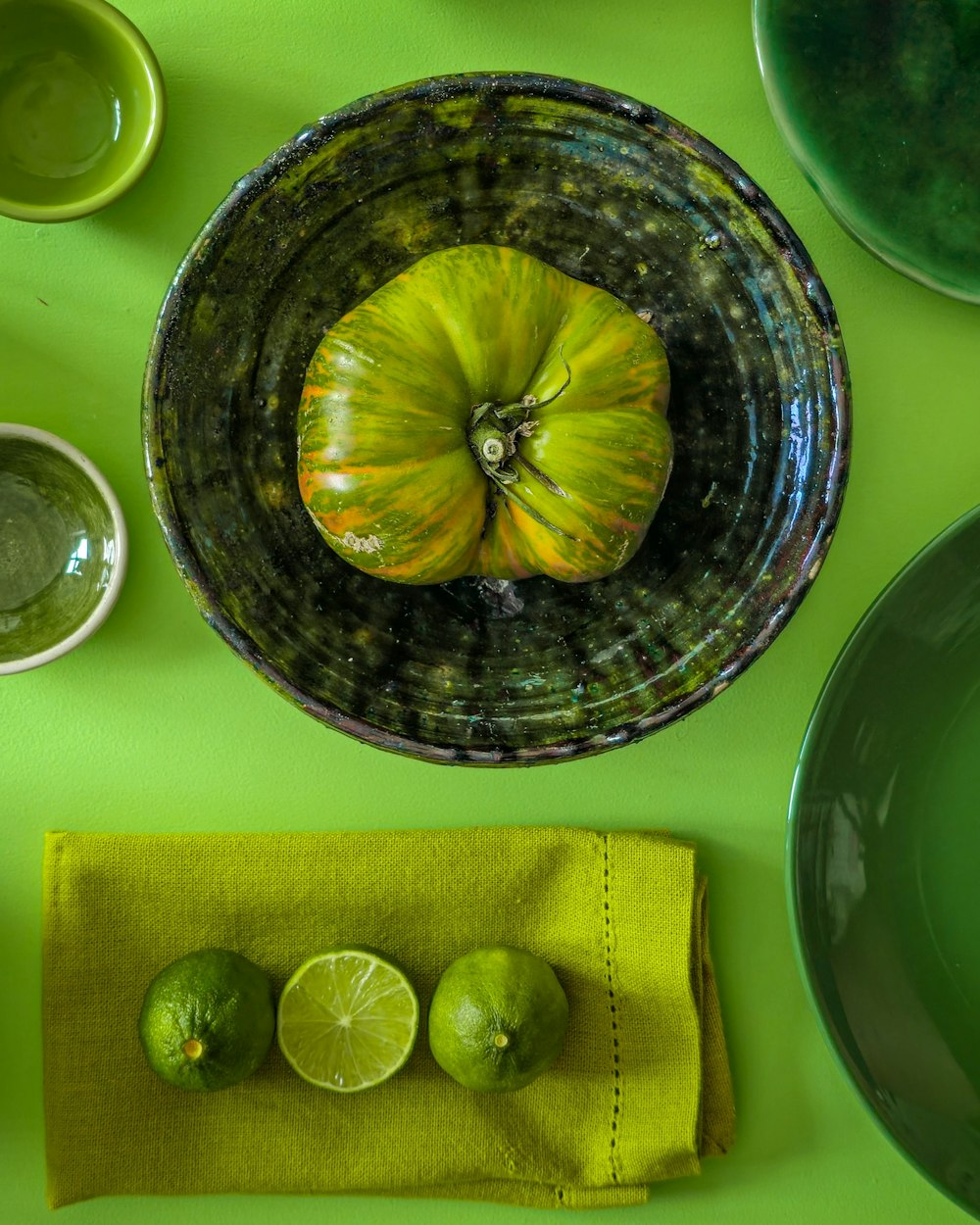 a green table topped with a bowl filled with fruit