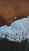 an aerial view of a beach with waves and sand