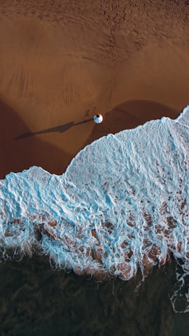 an aerial view of a beach with waves and sand