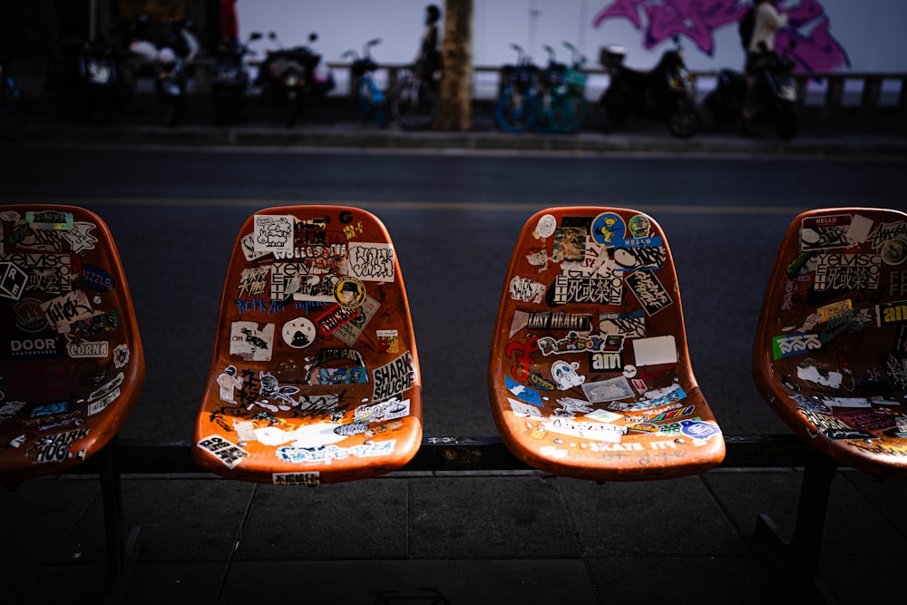 three orange seats with stickers all over them