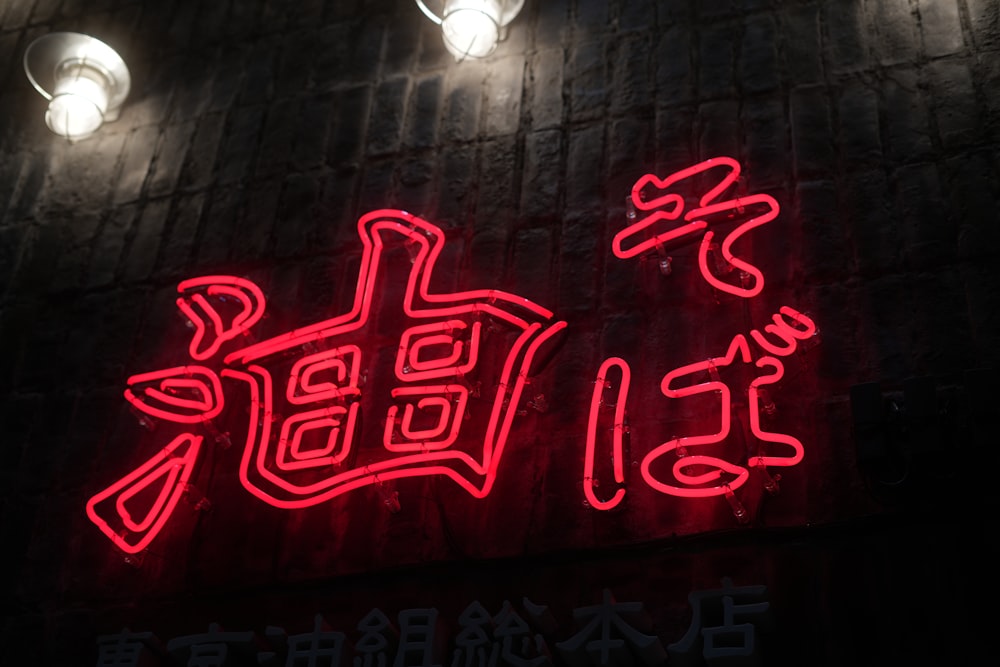 a neon sign with chinese writing on a brick wall