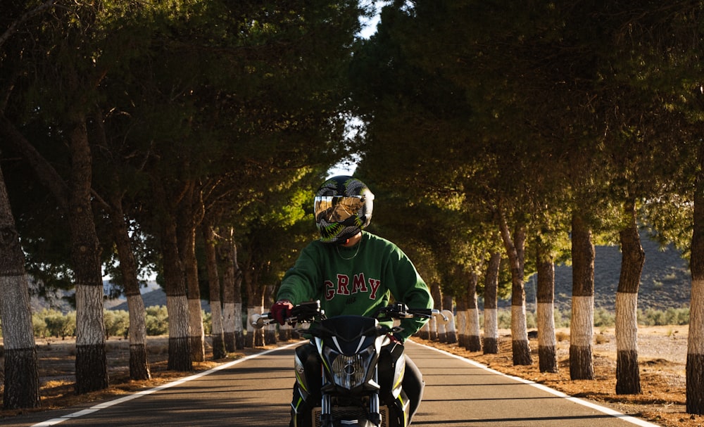 a man riding a motorcycle down a tree lined road
