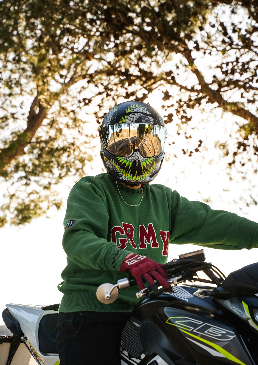 a person wearing a green shirt and a helmet on a motorcycle