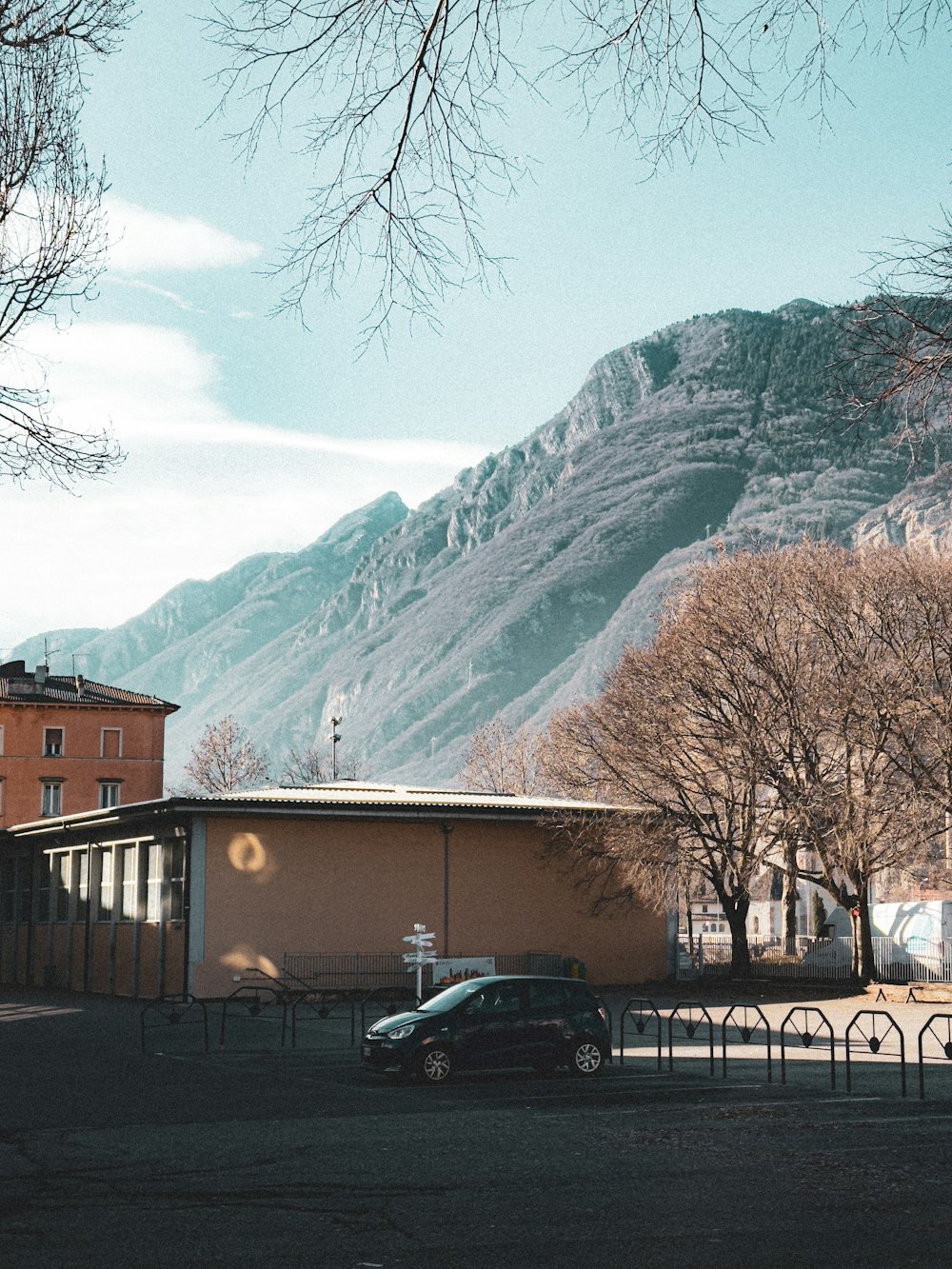 a car parked in front of a building with a mountain in the background