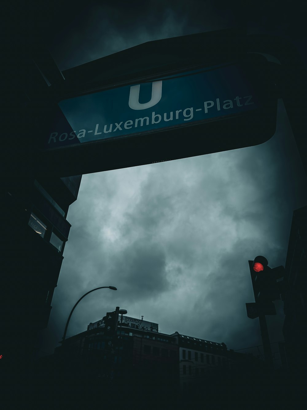 a red traffic light sitting under a cloudy sky