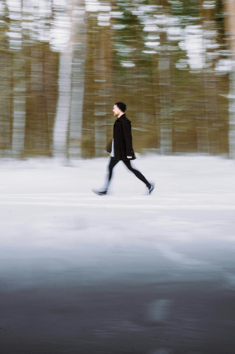 a man is walking in the snow in front of trees