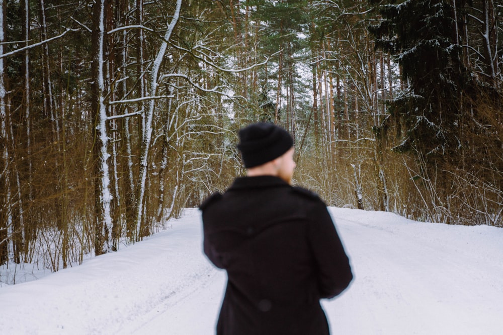 a person standing in the snow in front of a forest