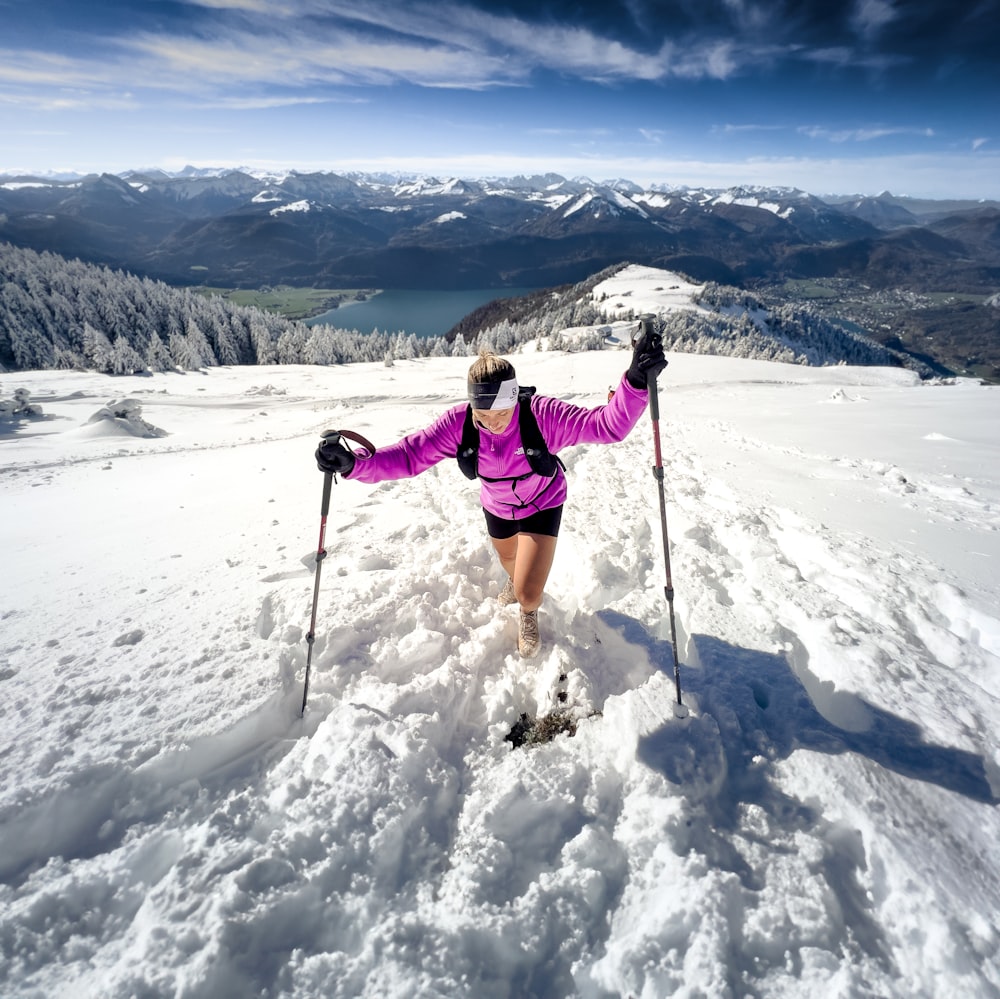 a woman in a pink jacket skiing on a mountain