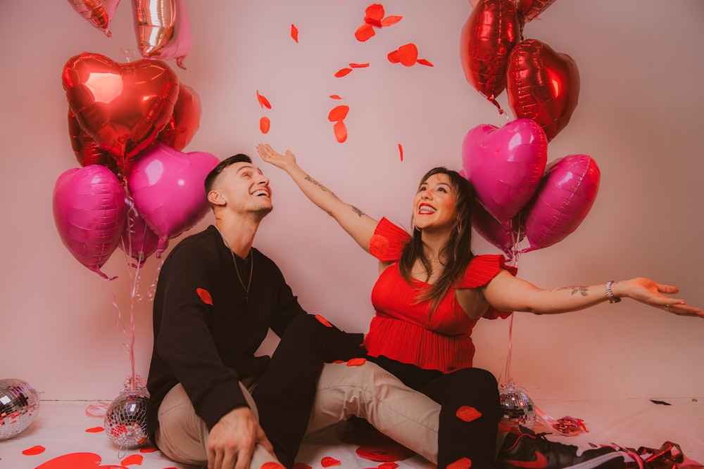 a man and a woman sitting on a floor with balloons