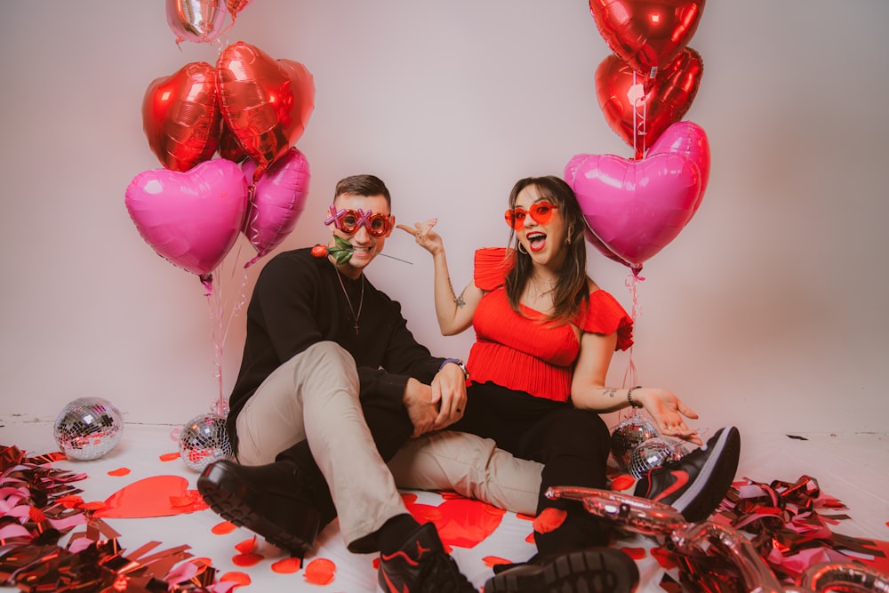 a man and a woman sitting on a floor with balloons and confetti