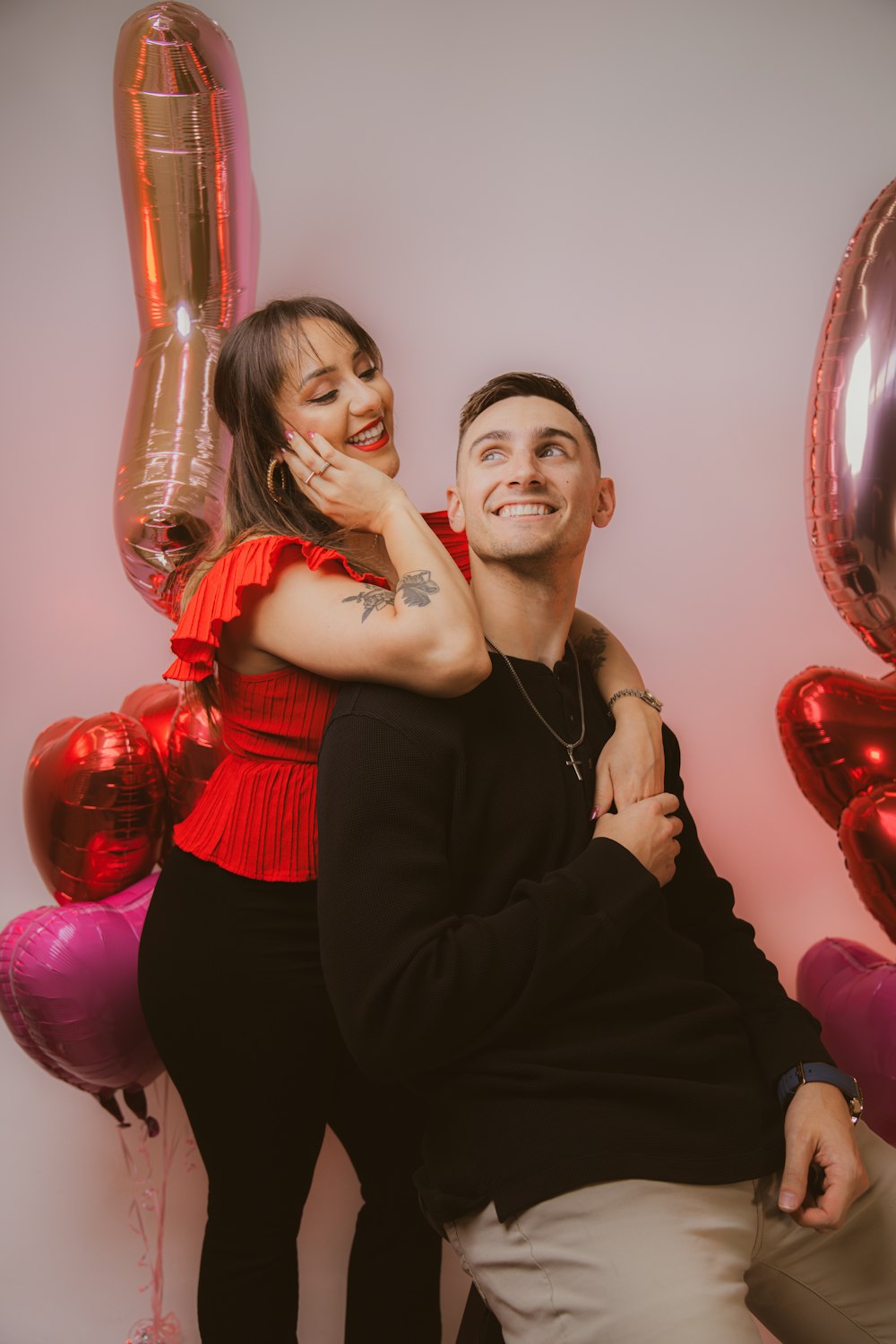 a man and a woman posing for a picture in front of balloons