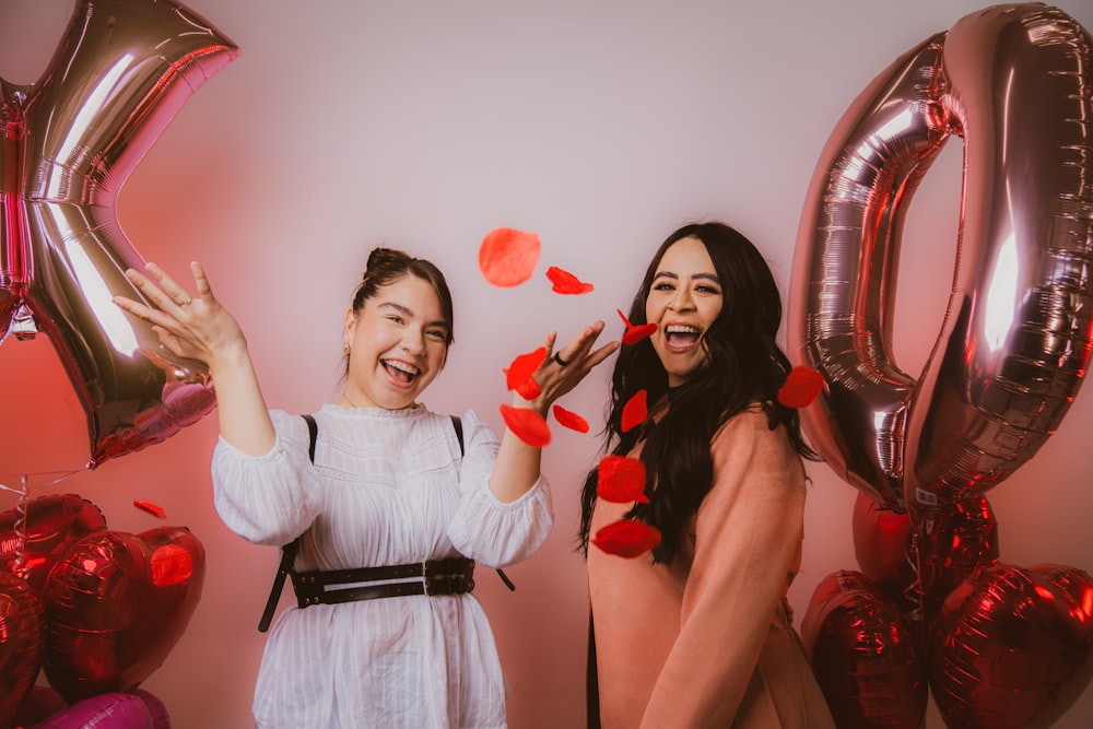 two women standing next to each other near balloons