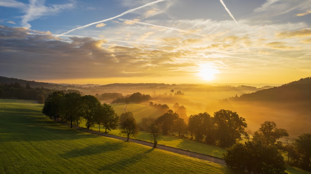 the sun is setting over a green field