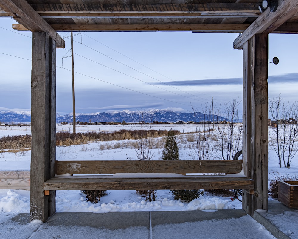 a wooden bench sitting in the middle of a snow covered field