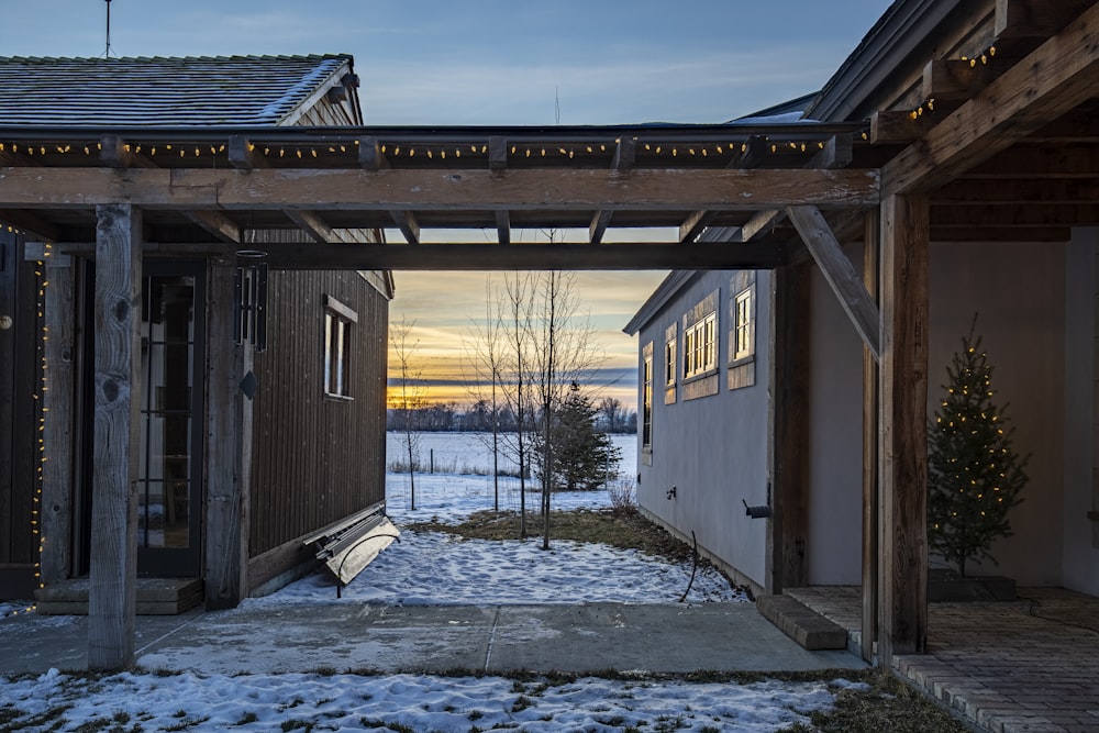 a wooden structure with a bench in the middle of a snowy yard