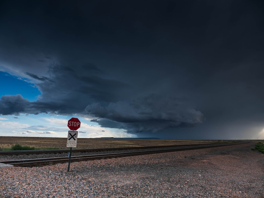 a red stop sign sitting on the side of a train track