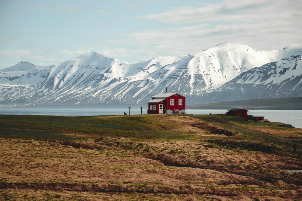 a red house sitting on top of a grass covered hill