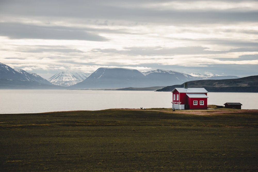 a red house sitting on top of a lush green field