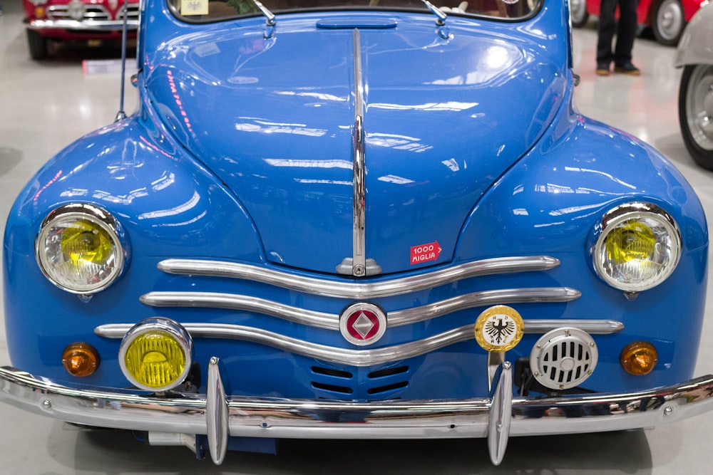 Un viejo coche azul está aparcado en una sala de exposición