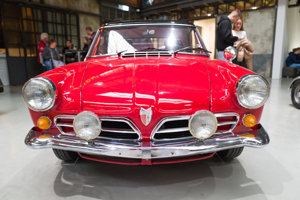 a red classic car is on display at a car show