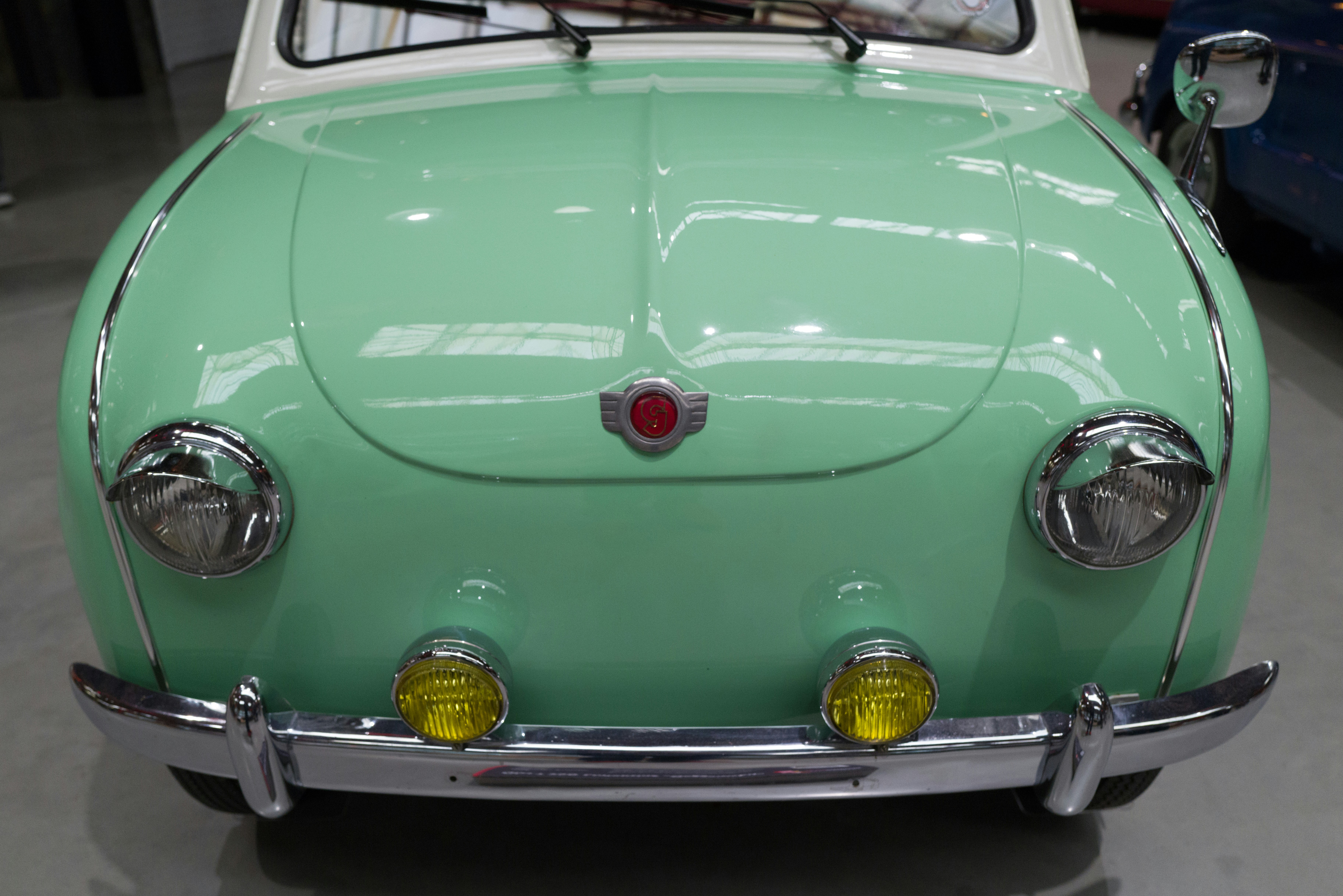Un viejo coche verde está aparcado en un garaje