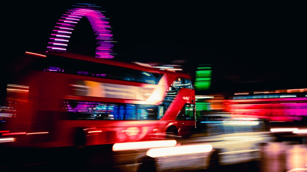 a double decker bus driving down a street at night