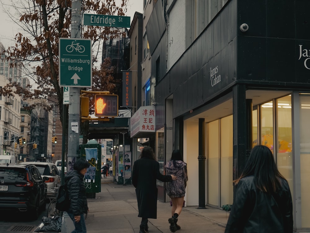 a group of people walking down a street next to tall buildings