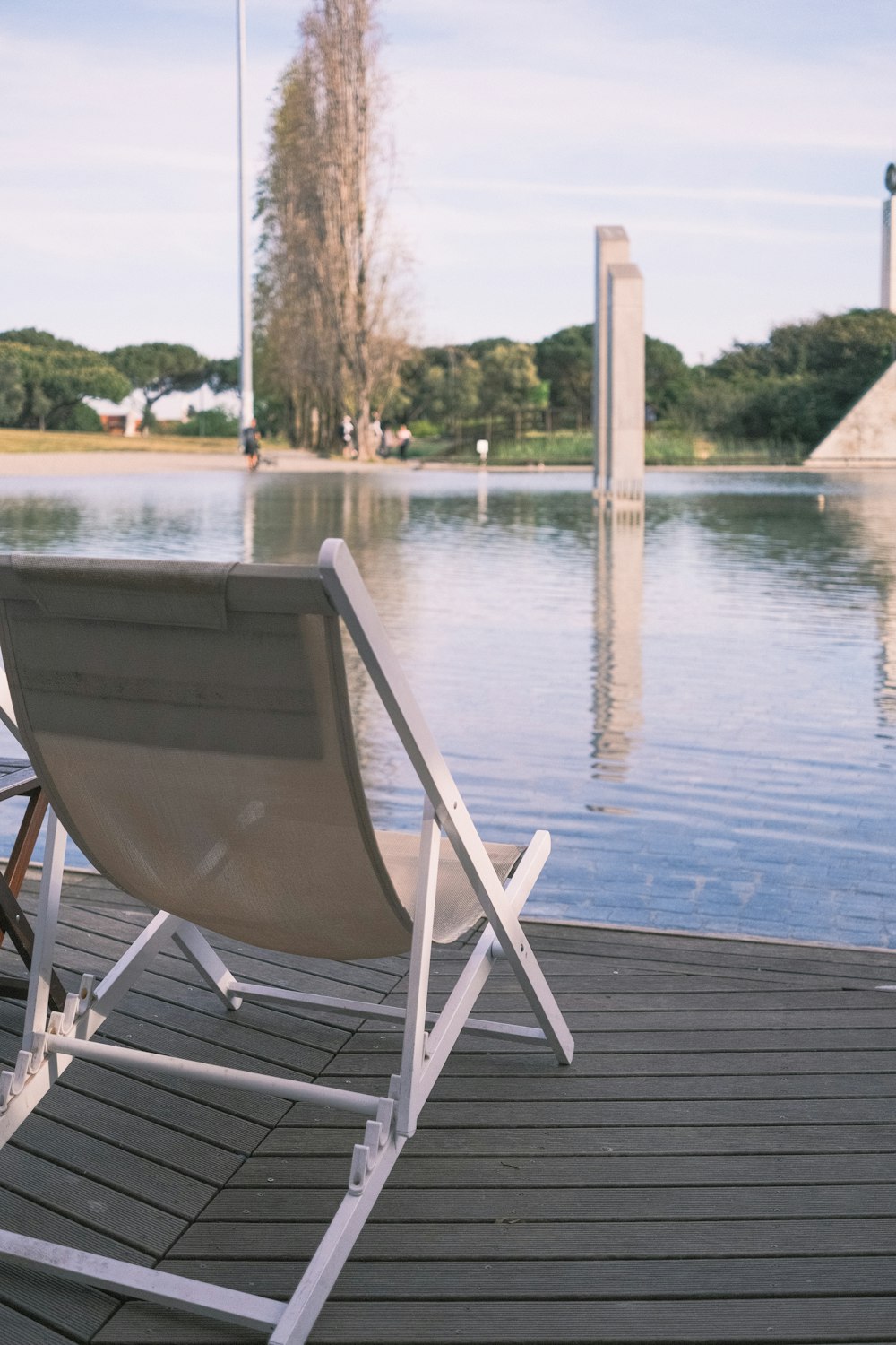 a lawn chair sitting on a dock next to a body of water