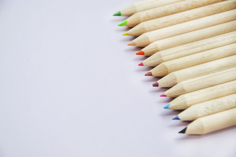 a row of colored pencils sitting on top of a white surface