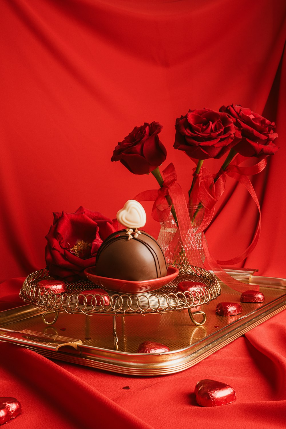 a gold tray with a chocolate covered cake and three red roses