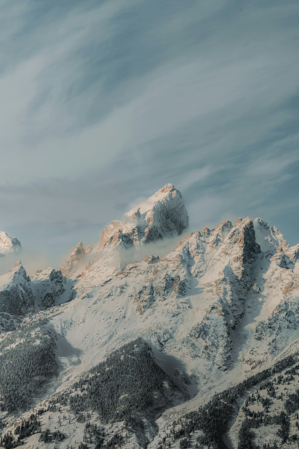 a snow covered mountain range under a cloudy sky