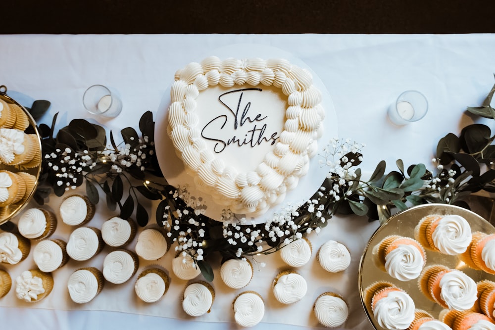 a table topped with a heart shaped cake and cupcakes