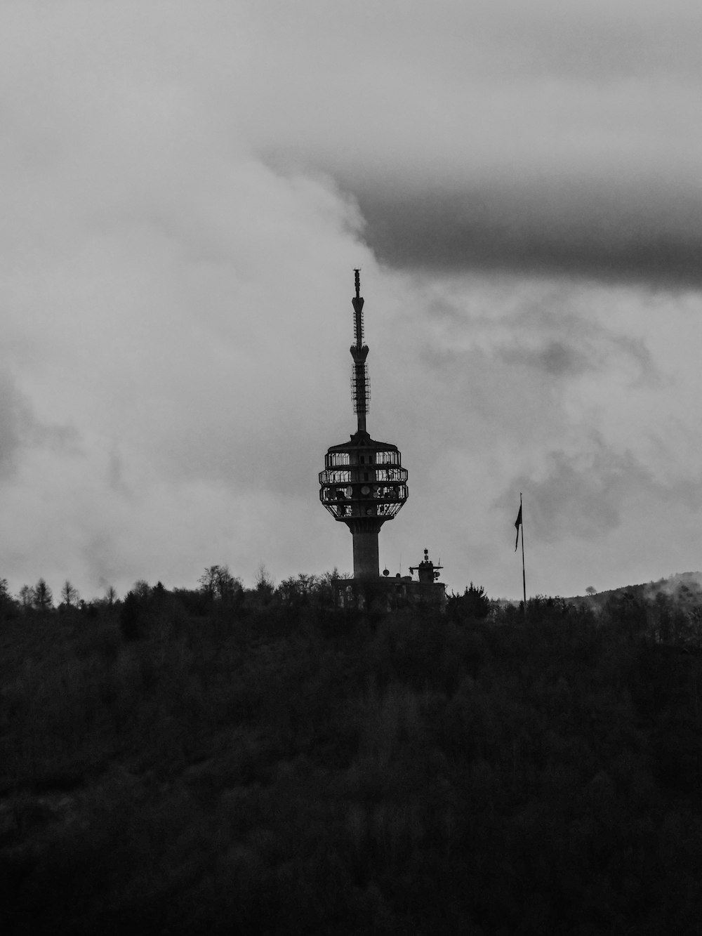 uma foto em preto e branco de uma torre em uma colina