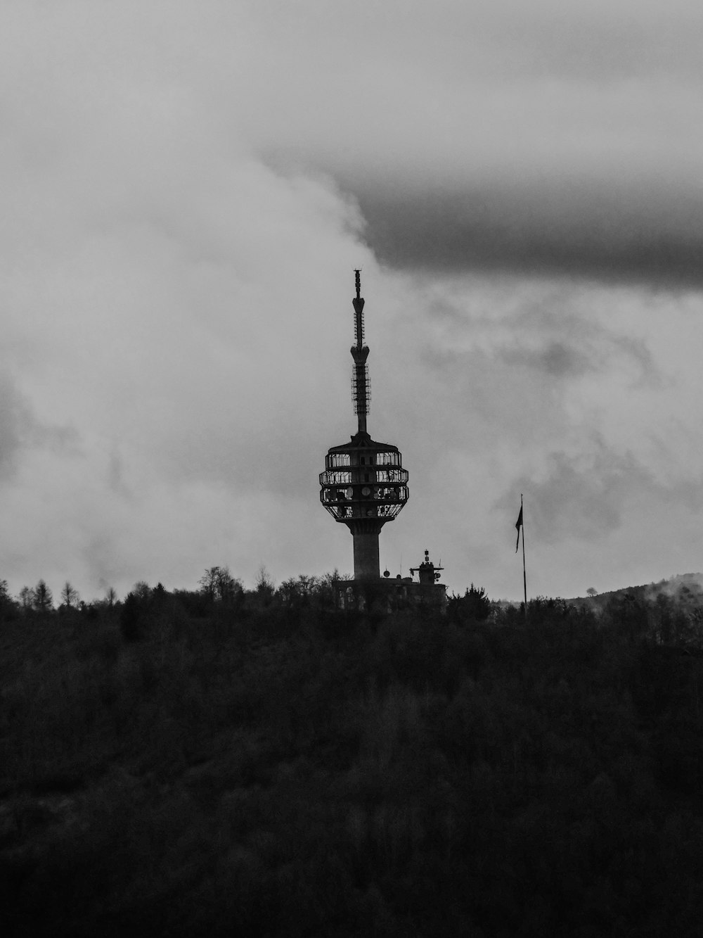 a black and white photo of a tower on a hill