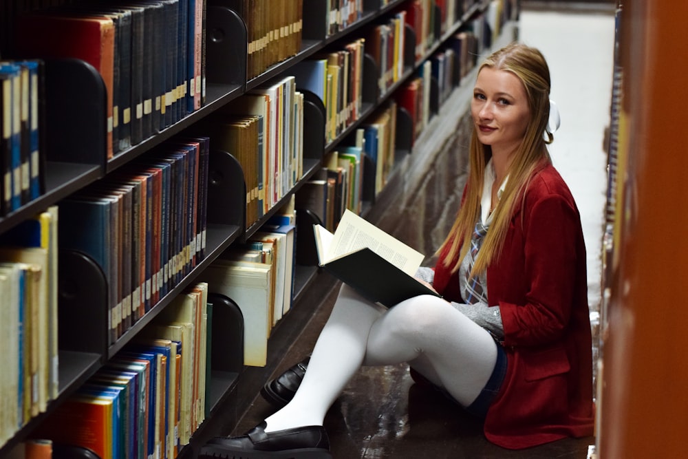 a woman sitting on the floor in a library reading a book