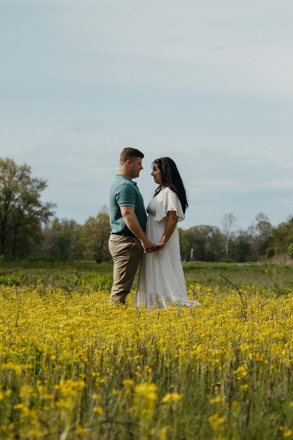 a man and woman standing in a field of yellow flowers