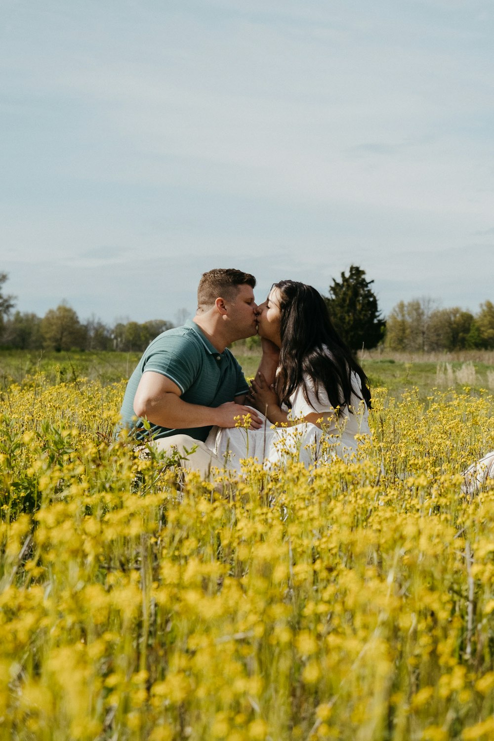 a man and woman kissing in a field of yellow flowers