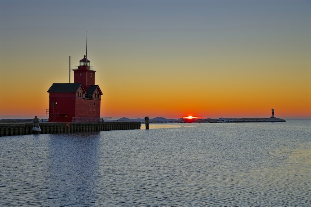 a red lighthouse sitting on top of a body of water