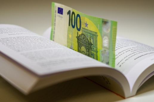 a hundred euros bill sticking out of an open book