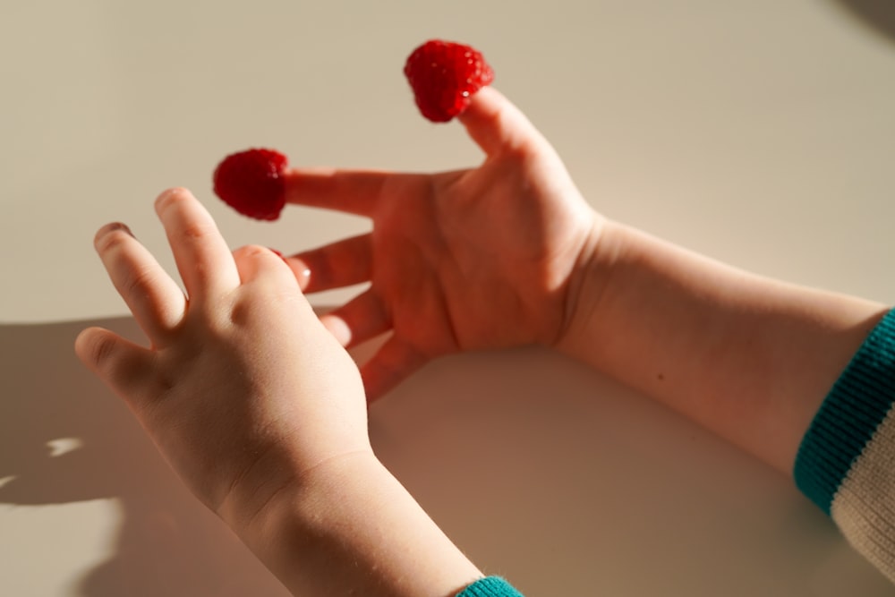 a person holding raspberries in their hands on a table