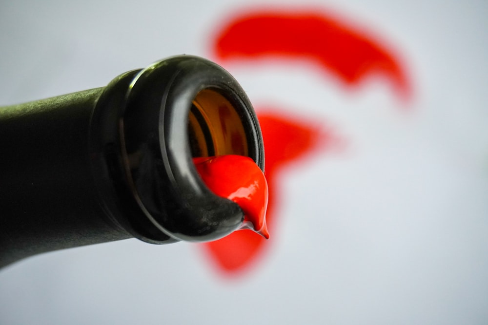 a close up of a red liquid in a black bottle